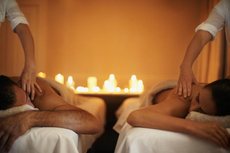 A couple get massages in a candle lit spa room