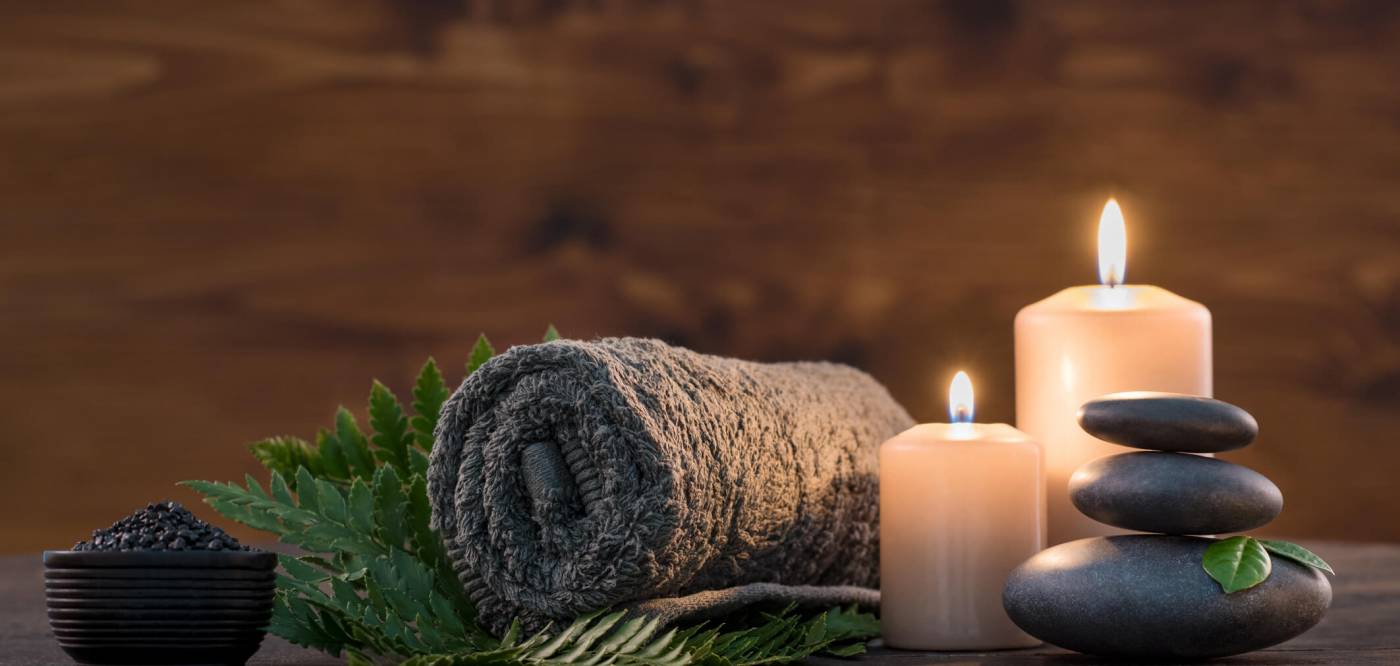 A towel, rocks, and candles prepared for a massage therapist to use